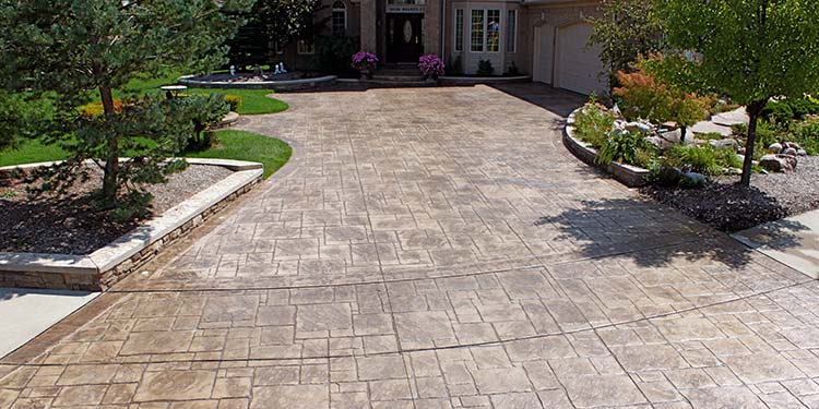 Large stamped concrete driveway with planter walls and lighting
