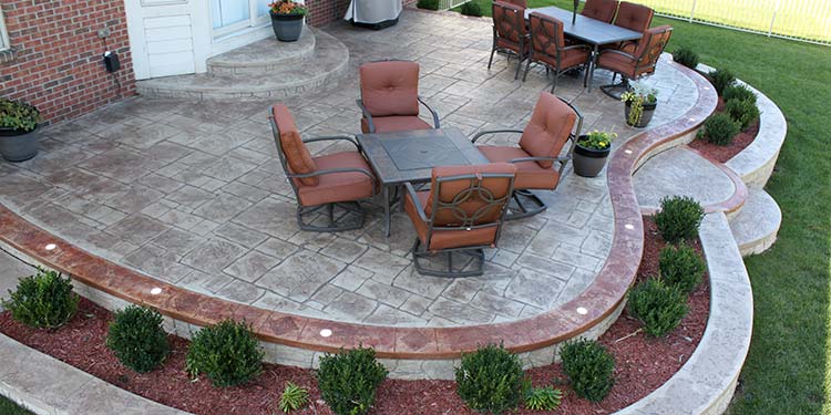stamped decorative concrete patio with stained borders and retaining walls